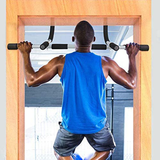 Man in a blue tank top and gray shorts doing pull-ups on a door frame.
