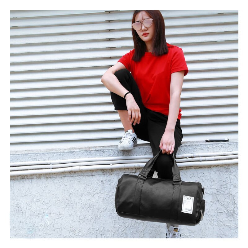 Woman wearing a red shirt poses with a waterproof sports gym bag on a ledge.
